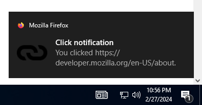 Example notification on Windows 10, located above the system clock, with a bold title reading "Click notification" followed by regular text reading "You clicked https://developer.mozilla.org/en-US/docs/MDN". The notification has a small Firefox logo in the top left corner that is followed by "Mozilla Firefox", and a link icon to the left of the primary notification text.